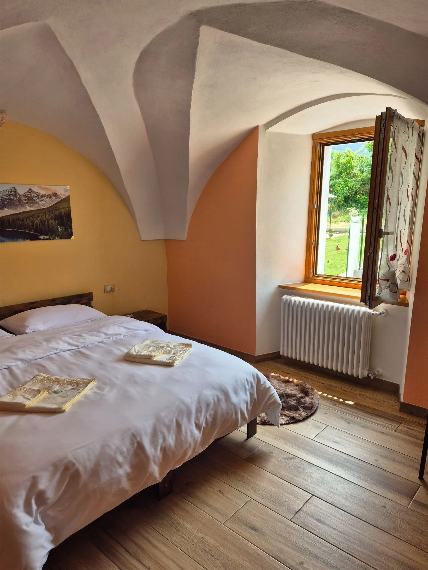 Camera Larissa con soffitto a volta, finestra aperta e luce sul giardino