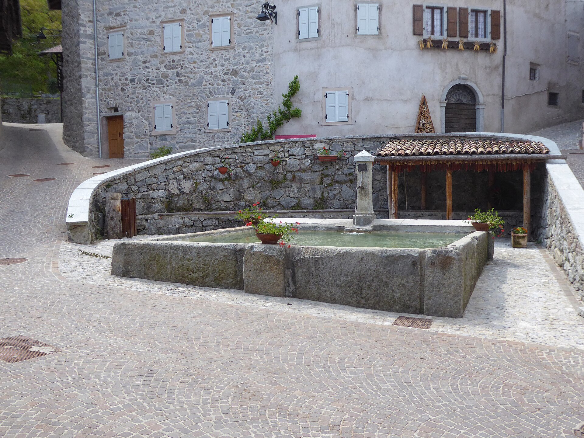 Fontana storica e case rurali in pietra nel borgo di Rango